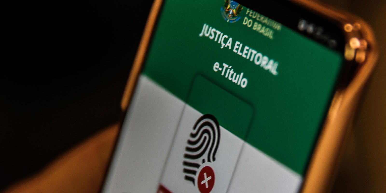 As eleições de 2022 têm se tornado uma realidade cada vez mais próxima. Mas não basta se dirigir às urnas e dar seu voto, é preciso estar em posse do título de eleitor no ato, documento responsável por identificar o cidadão e comprovar o seu comparecimento. Embora a emissão do título de eleitor já fosse um procedimento relativamente tranquilo mesmo no modelo presencial, agora, com a evolução tecnológica ficou ainda mais fácil e rápido. Até o dia 1º de outubro, véspera do primeiro turno das eleições de 2022, os eleitores conseguem emitir a versão digital do documento. É importante lembrar que de acordo com o artigo 14 da Constituição Federal, nas eleições de de 2022, o voto é obrigatório para todo e qualquer cidadão com 18 anos de idade ou mais. Por outro lado, é um procedimento facultativo para os jovens na faixa etária de 16 e 17 anos. Por onde emitir o título de eleitor digital para as eleições de 2022? A emissão deve ser feita pelo sistema TítuloNet, que pode ser acessado tanto pelo computador, quanto tablet e celular. Posteriormente basta clicar na opção "não tenho" e depois em "Título de Eleitor". Por fim, será necessário preencher todo o formulário com informações pessoais como o nome completo, e-mail, número do RG, local e data de nascimento. Na sequência, o solicitante do título deve anexar ao menos quatro fotos junto ao requerimento para comprovar a identidade. A primeira deve ser uma selfie segurando algum documento de identidade oficial. As próximas duas devem ser da própria documentação utilizada para comprovar a identificação da primeira foto. Por fim, a terceira imagem deve ser de um comprovante de residência. Se tratando da emissão do título de eleitor por homens na faixa etária de 18 a 45 anos de idade, também será preciso enviar uma foto do comprovante de quitação junto ao serviço militar. Vale ressaltar que as imagens devem estar em boa resolução e, portanto, totalmente legíveis. Do contrário, há a possibilidade de ter o pedido negado pela Justiça Eleitoral. A solicitação do título de eleitor pode ser acompanhada pela internet, basta acessar a guia "Acompanhar Requerimento" e informar o número do protocolo gerado na primeira fase do atendimento. Processados todos os dados sem nenhuma pendência, o eleitor pode baixar o aplicativo e-Título no celular, e começar a usar a versão digital do documento, dispensando a necessidade e obrigatoriedade do título de papel. A plataforma possibilita o rápido e fácil acesso a todas as informações pessoais armazenadas em um banco de dados da Justiça Eleitoral. Como usar o título de eleitor digital nas eleições de 2022? Lançado em 2018, o e-Título é o aplicativo da Justiça Eleitoral que substitui no dia das eleições o tradicional título de eleitor impresso. O documento eletrônico pode ser baixado em qualquer plataforma para uso no celular ou no tablet, oferece diversas facilidades e permite o acesso rápido a informações eleitorais. Além de fornecer a via digital do título de eleitor, o e-Título serve para gerar certidões de quitação eleitoral e de crimes eleitorais, emitir e pagar multas, consultar o local de votação, justificar a ausência às urnas e se inscrever como mesário voluntário, entre outros serviços, eliminando a necessidade de se dirigir a um cartório eleitoral. Para utilizar o e-Título, o eleitor deve inserir o número do título ou do CPF, seu nome, nome da mãe e do pai e data de nascimento. Depois, é só seguir os passos indicados. O eleitor que já tenha feito o cadastramento biométrico (impressão digital, fotografia e assinatura) terá uma fotografia na sua versão do e-Título, facilitando a identificação na hora do voto. Caso contrário, deverá levar outro documento oficial com foto para se identificar ao mesário no dia da votação. Como regra, não é preciso ter o título de eleitor em mãos, caso a pessoa saiba a seção e o local em que vota. Basta levar um documento oficial com foto.