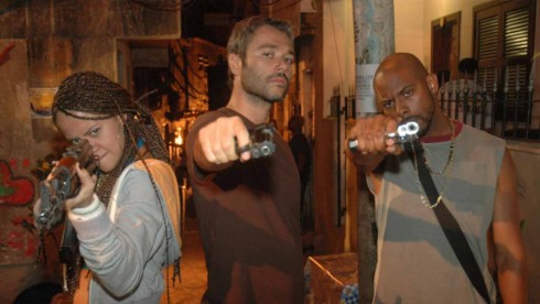 Cena de A Lei e o Crime com personagens mirando arma para a câmera